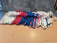Stack of white, blue and pink child-size plastic hangers on tabletop