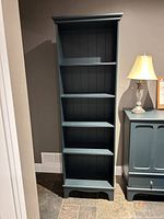 Front view of tall dark teal IKEA LOMMARP bookcase showing five shelves
