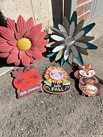 Group view of two metal flowers and three wood plaques
