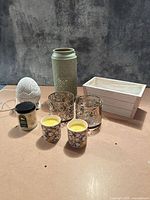 Group shot of all eight items including holders, warmer, jar candle, votives and crate