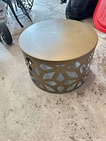 Full view of the round metal coffee table showing the cutout base