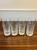 Four clear cut crystal highball glasses side by side