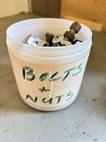 Plastic tub labeled Bolts + Nuts containing mixed fasteners