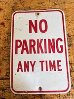 Front view of the aluminum No Parking Any Time sign showing text, border, mounting holes and visible wear