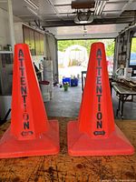 Two orange traffic cones side by side on workbench