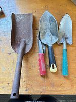 All four steel hand trowels/shovels laid out on workbench