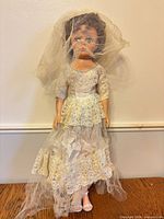 Full view of bride doll in lace gown and veil standing upright