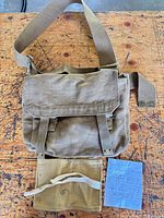 Front of shoulder bag with flap closed, tool roll displayed beside