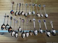 All 23 souvenir spoons laid out showing fronts