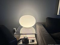 Lamp illuminated on clear side table, showing full spherical shape