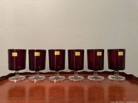 Six ruby red Luminarc stemmed wine glasses lined up