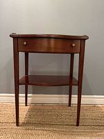 Front view of mahogany end table showing drawer, shelf, legs