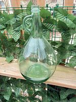 Full view of aqua glass demijohn jug on railing