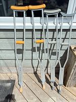 Four aluminum crutches leaning against wall on deck