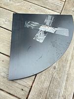 Top view of black quarter-circle shelf with tape residue