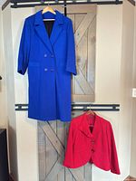 Full view of both garments hanging: blue long coat above, red short jacket below