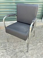Front angled view of chair showing black vinyl upholstery and chrome frame