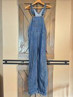 Full view of blue Dickies denim overalls hanging