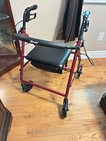Front angled view of Drive red rollator showing seat, backrest, wheels