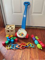 Group shot of all toys including popper, shape sorter, blocks, rings, beads