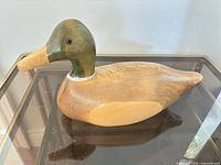 Left side profile of wooden duck decoy on glass surface