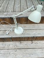 Full view of white IKEA SEKUND adjustable desk lamp on wooden steps