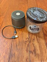 Speaker, charging cable, packaging jar on wooden floor