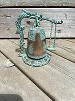 Full view of bell on dragon stand showing overall design and patina