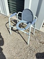Front view of full commode showing frame, seat opening and armrests