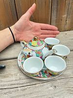 Full set in hand for scale showing teapot, lid, tray and cups