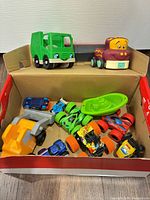 Overview of box containing assorted plastic toy vehicles