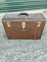 Closed brown toolbox front showing latches and handle