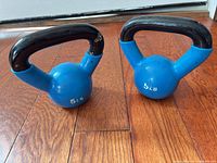 Pair of blue 5 lb kettlebells on wood floor