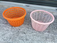 Orange and pink plastic laundry baskets side by side