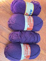 Four purple Patons wool skeins stacked showing labels