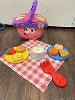 Overall view of picnic basket, plates, food pieces, cloth and fork