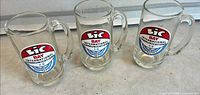 Three glass mugs with BIC logos front view