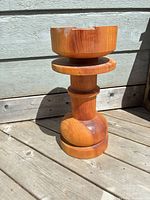 full view of solid wood pedestal plant stand on deck