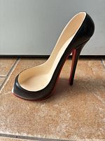 Left side view of black stiletto wine holder showing red sole and heel