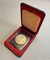 Open display box showing coin in plastic holder inside red velvet tray