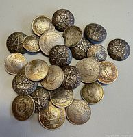 Mixed pile of coin-style metal buttons showing both star and bust designs