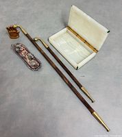 Group shot showing onyx box open, two kiseru pipes, brass hand, metal inkwell stand