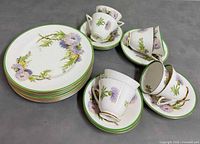 Stack of eight plates and seven teacup and saucer sets displayed