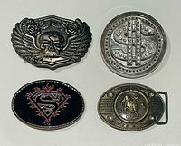 Front view of four belt buckles displaying designs