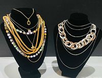 All necklaces displayed on two black busts showing variety of styles and metals