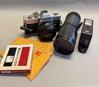 Group image showing camera with lens, Tamron zoom lens, Braun flash, Rollei filter box and Kodak envelopes