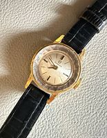 Close-up of watch face showing Omega logo, dial layout, gold-tone case