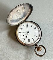 Open silver pocket watch showing dial with Roman numerals and seconds sub-dial