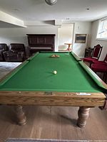 Full view of 8 ft oak pool table with green cloth and accessories on playing surface