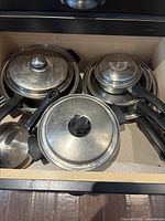 Drawer view showing all saucepans, frying pans, and lids nested together